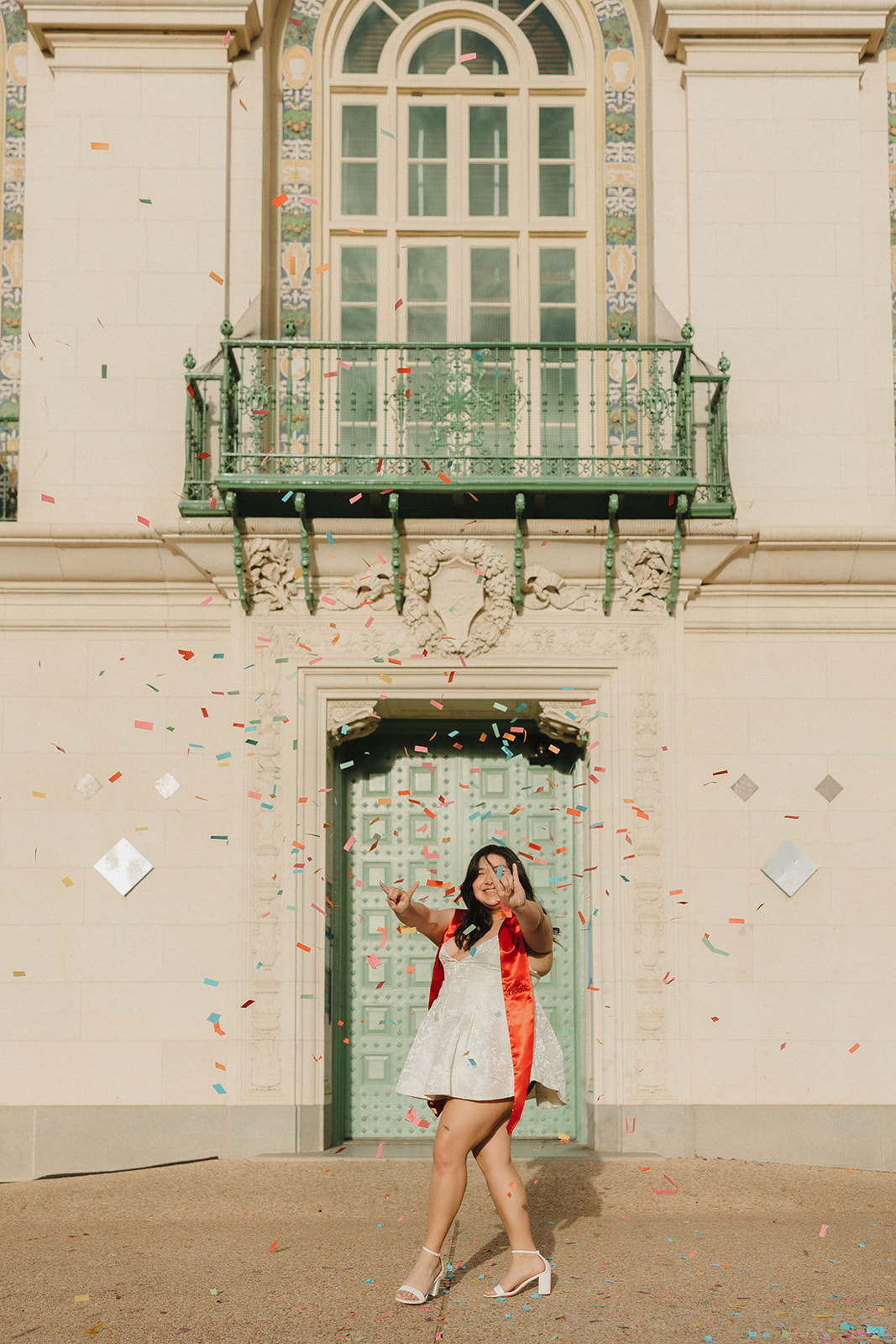 UT Austin senior pictures in front of the blue doors of the architecture library popping confetti