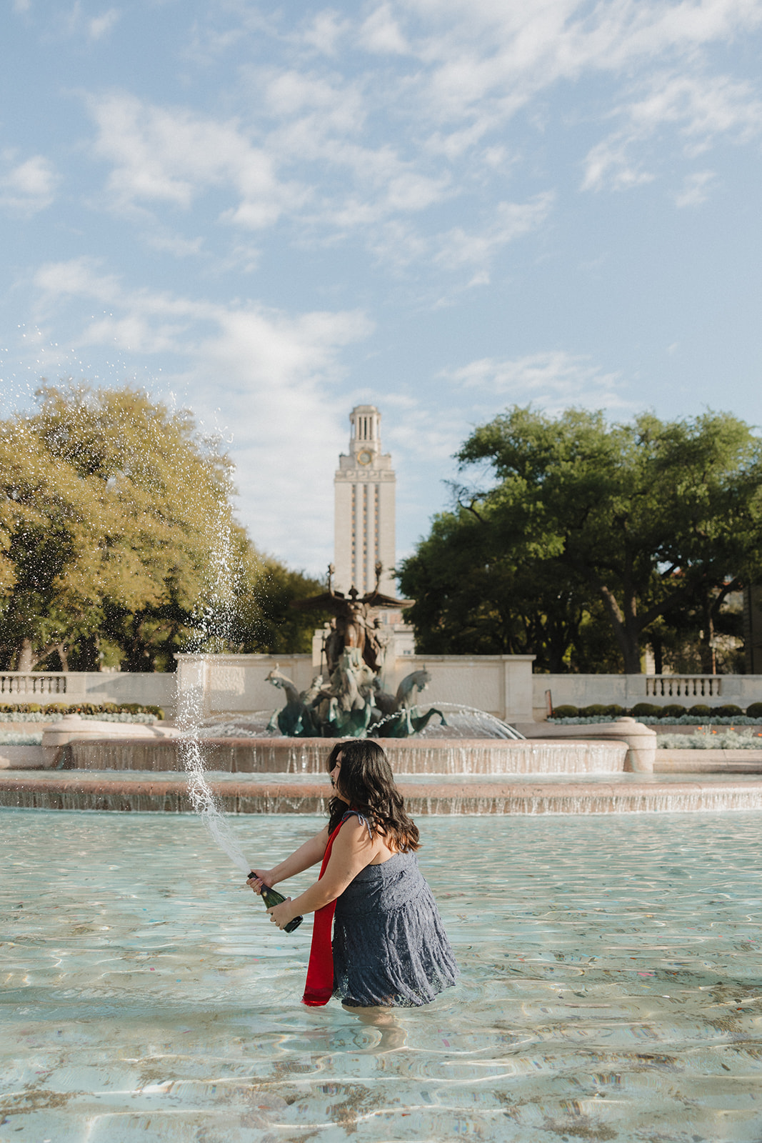 UT Austin senior pictures in little field fountain popping champagne