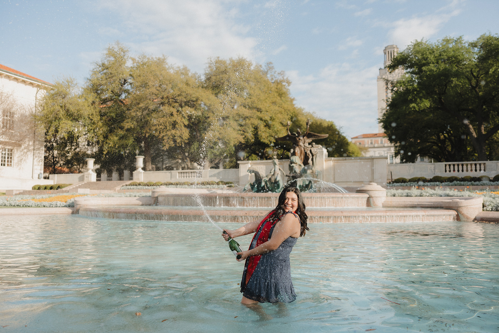 UT Austin senior pictures in little field fountain popping champagne