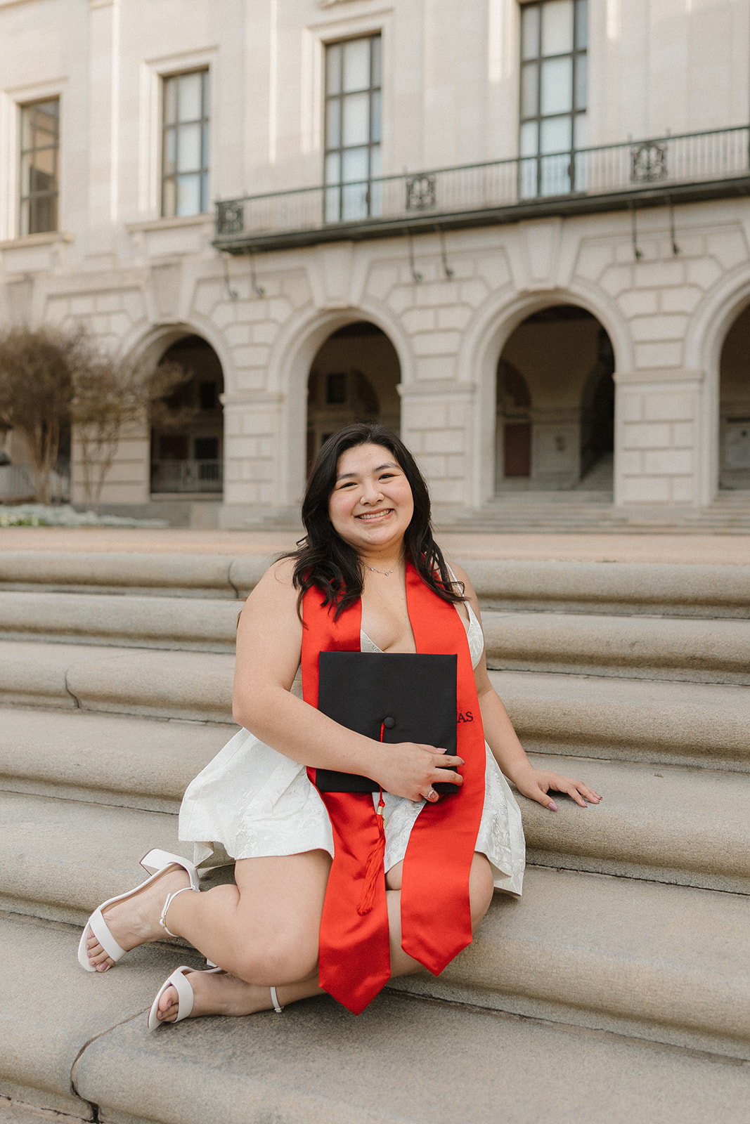 UT Austin senior pictures on the steps in front of the tower girl holding graduation cap