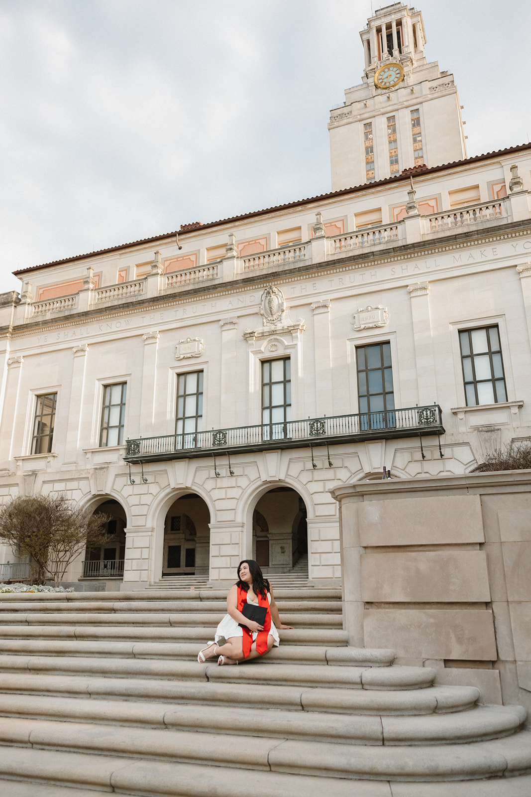 UT Austin senior pictures on the steps in front of the tower girl holding graduation cap