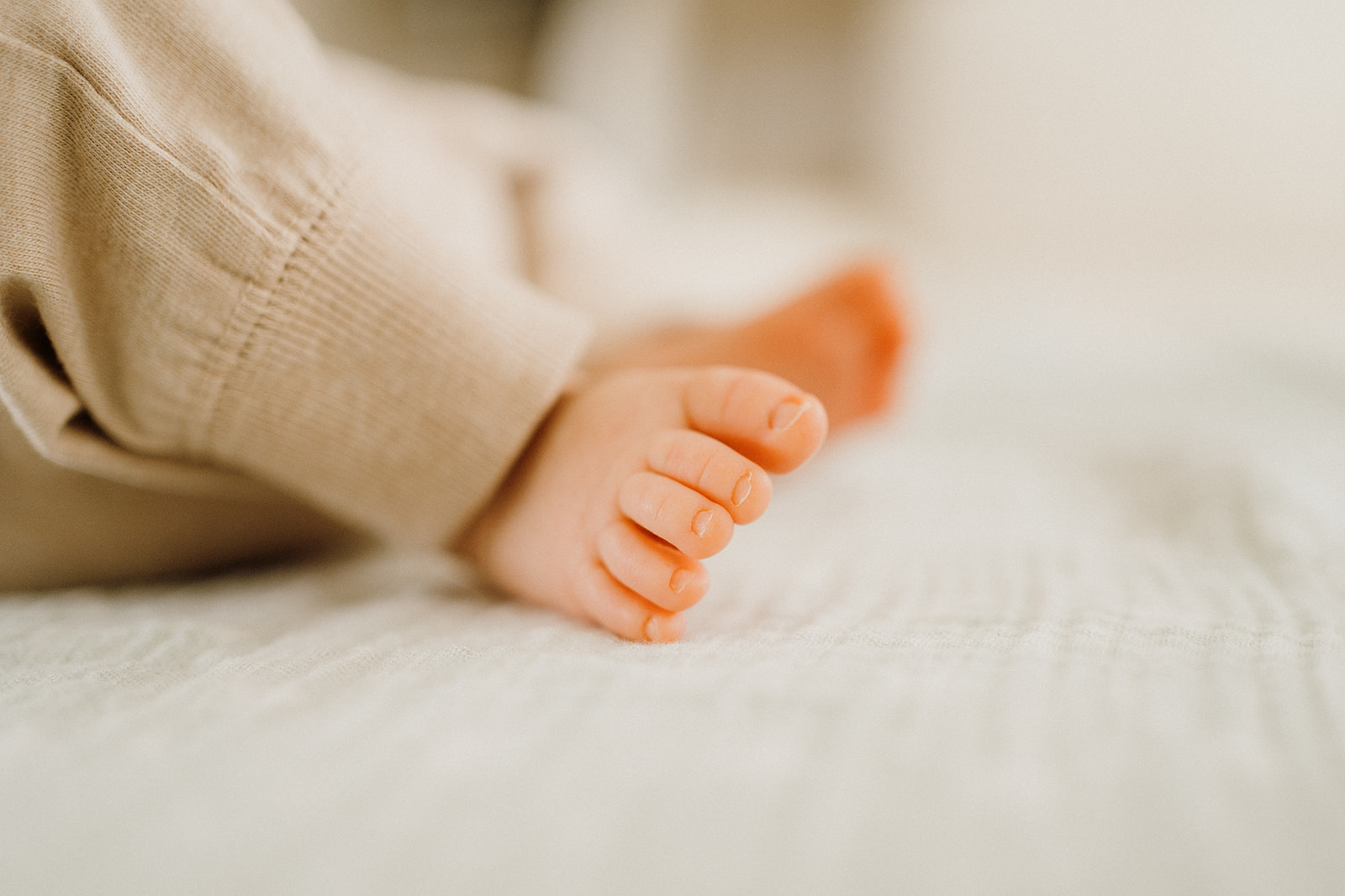 Newborn toes on the bed.