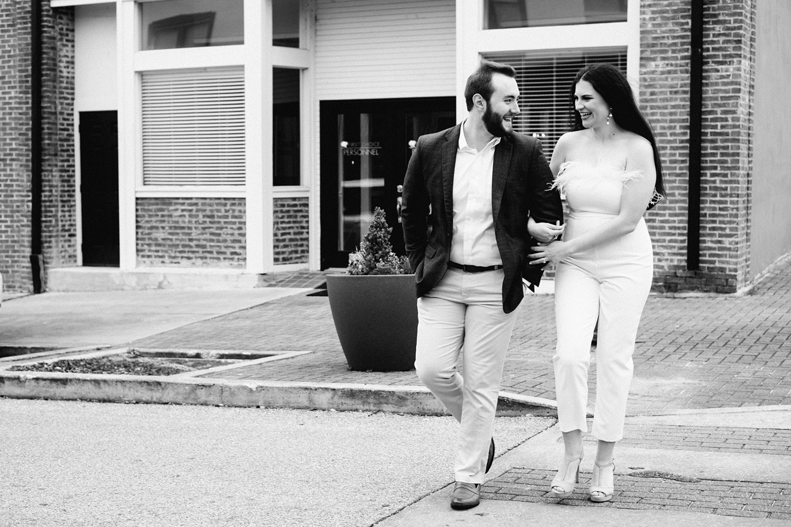 engaged couple crosses the street laughing and having a fun time during their downtown opelika alabama engagement sessio