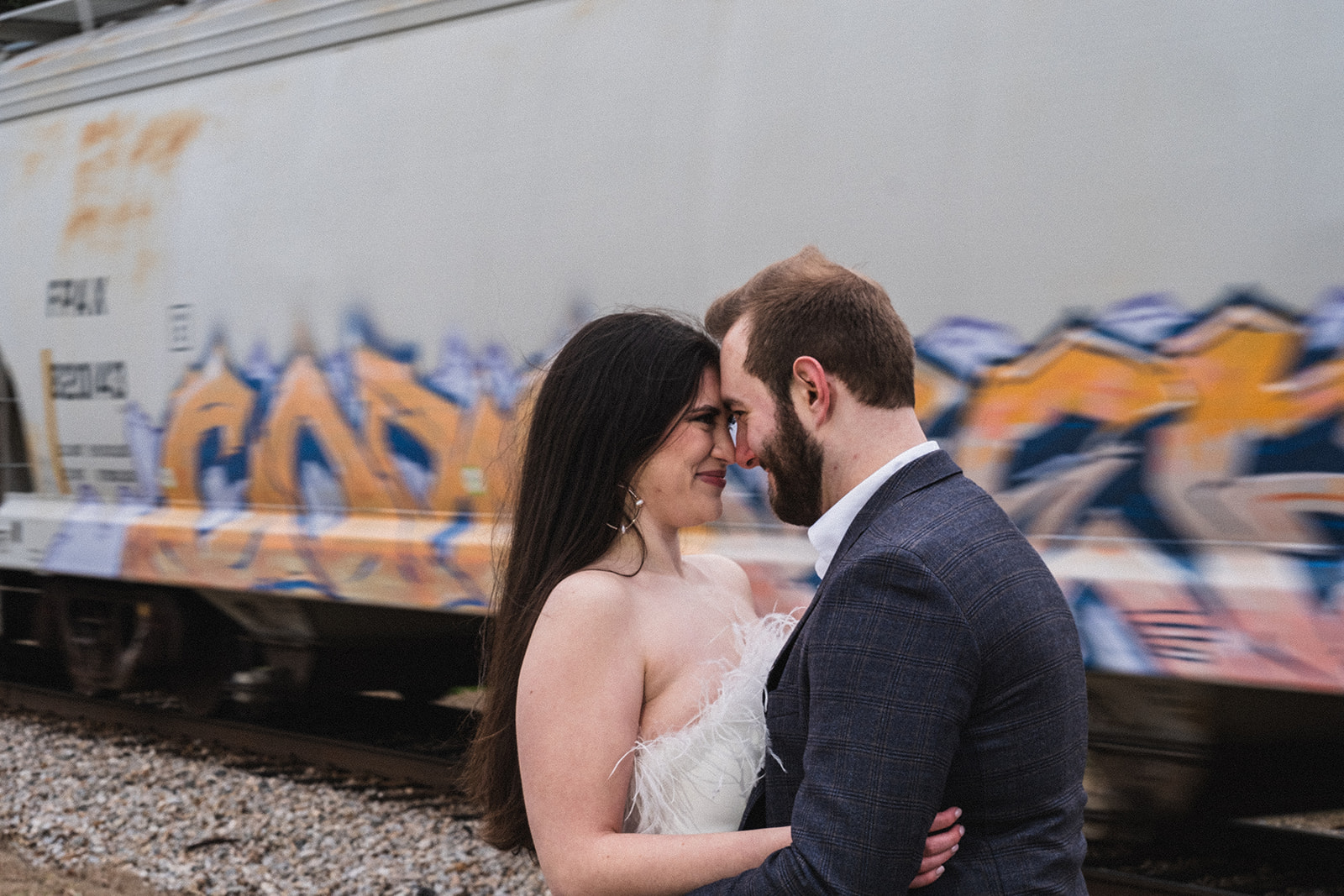 engaged couple posing in front of a moving train coming through downtown opelika alabama