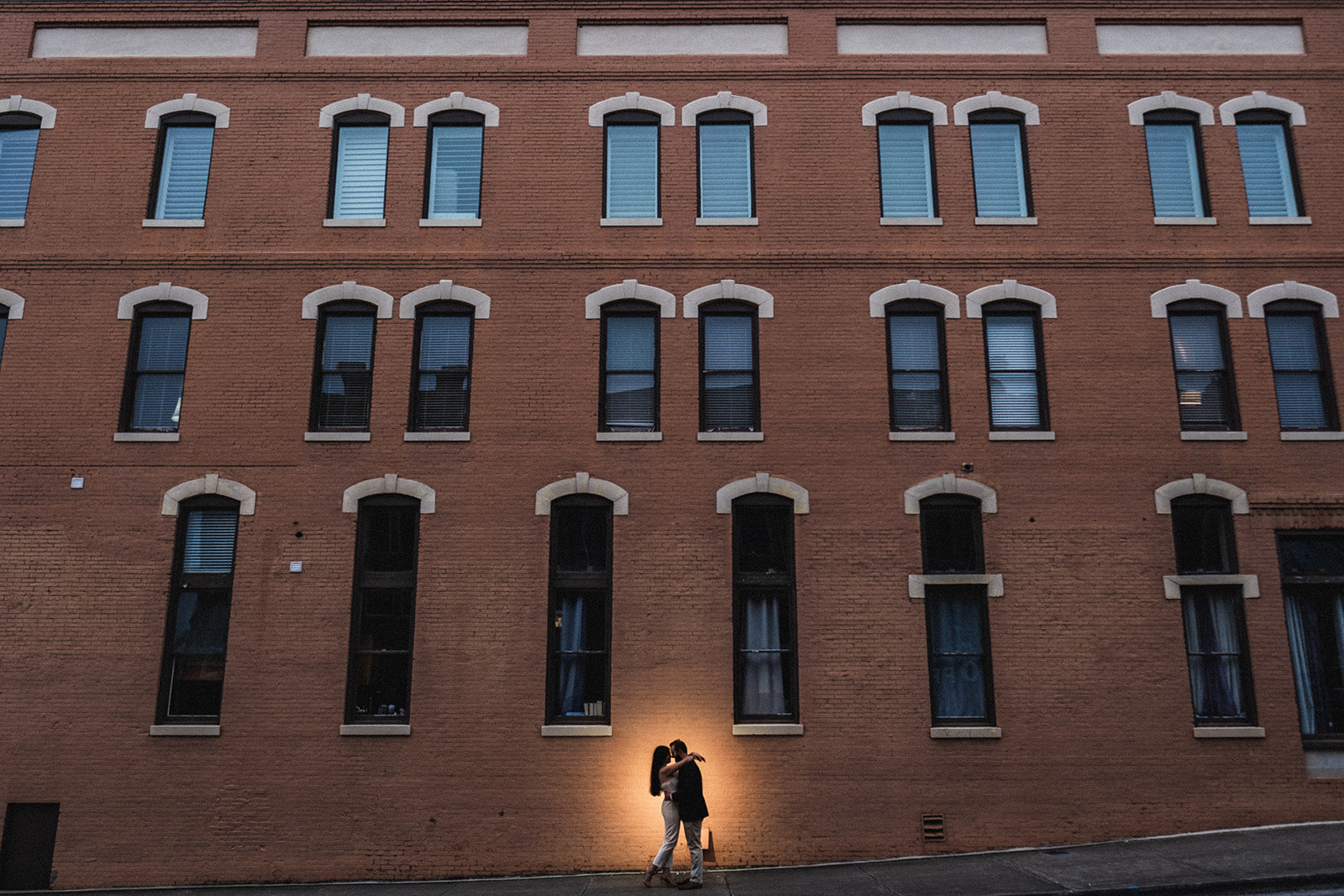 A romantic engagement session in Opelika Alabama with the couple silhouetted against a gorgeous historic building.