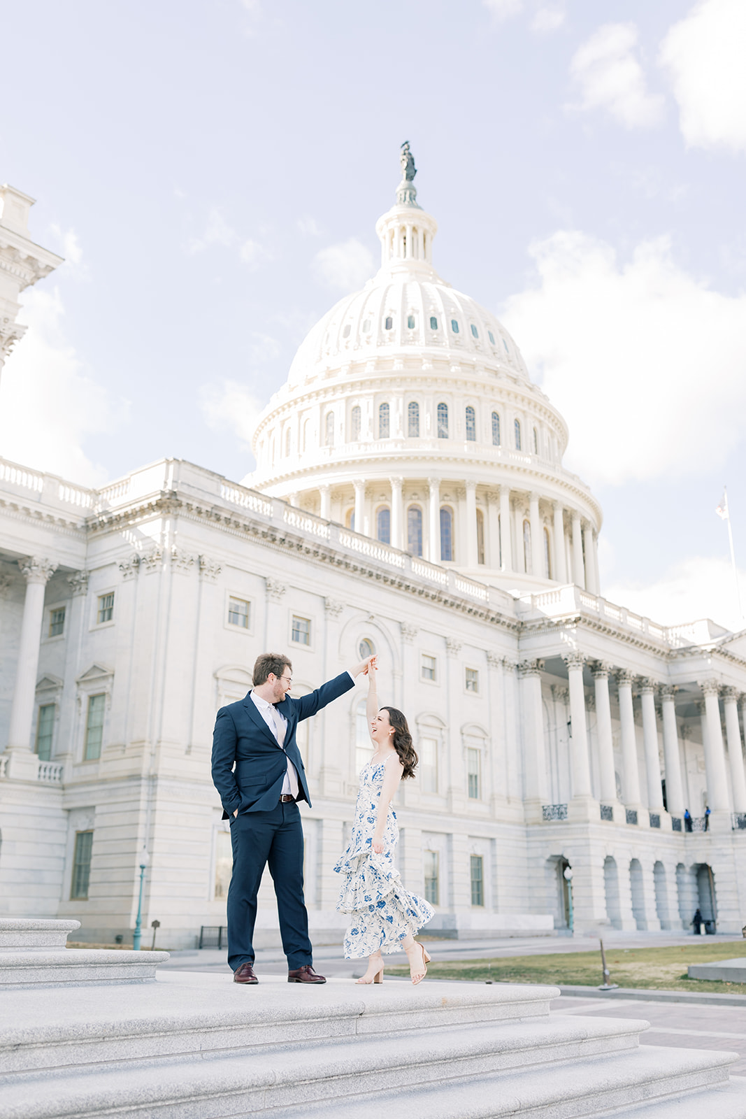 An engaged couple climbs the steps of the U.S. Capitol Building during their winter engagement session