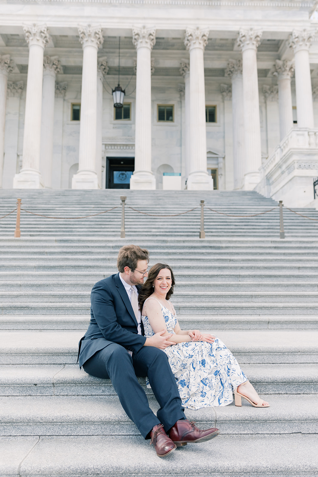An engaged couple climbs the steps of the U.S. Capitol Building during their winter engagement session