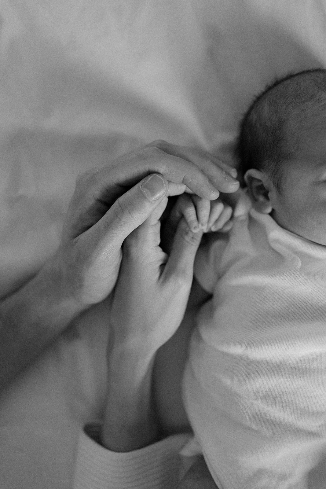 a baby's hand encompassed in mothers and fathers hand.