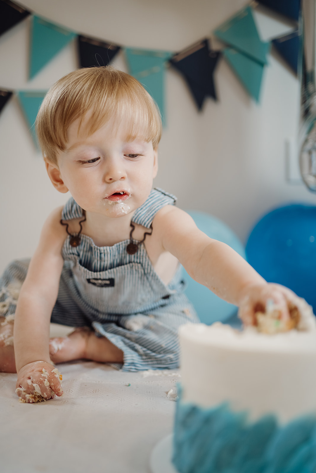 A little boy reaching for cake.