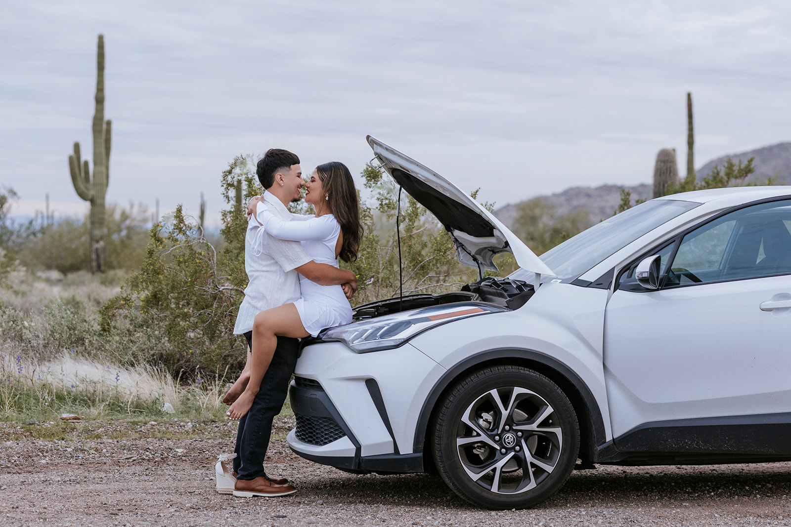 bride and groom sitting on the hood of their cars while we (photography Is Unique ) Take their portrait in Arizona