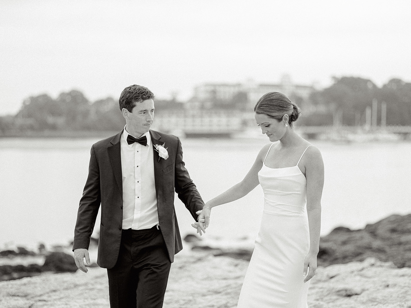 Bride and groom walking along the coast at their Wentworth By The Sea Country Club wedding.