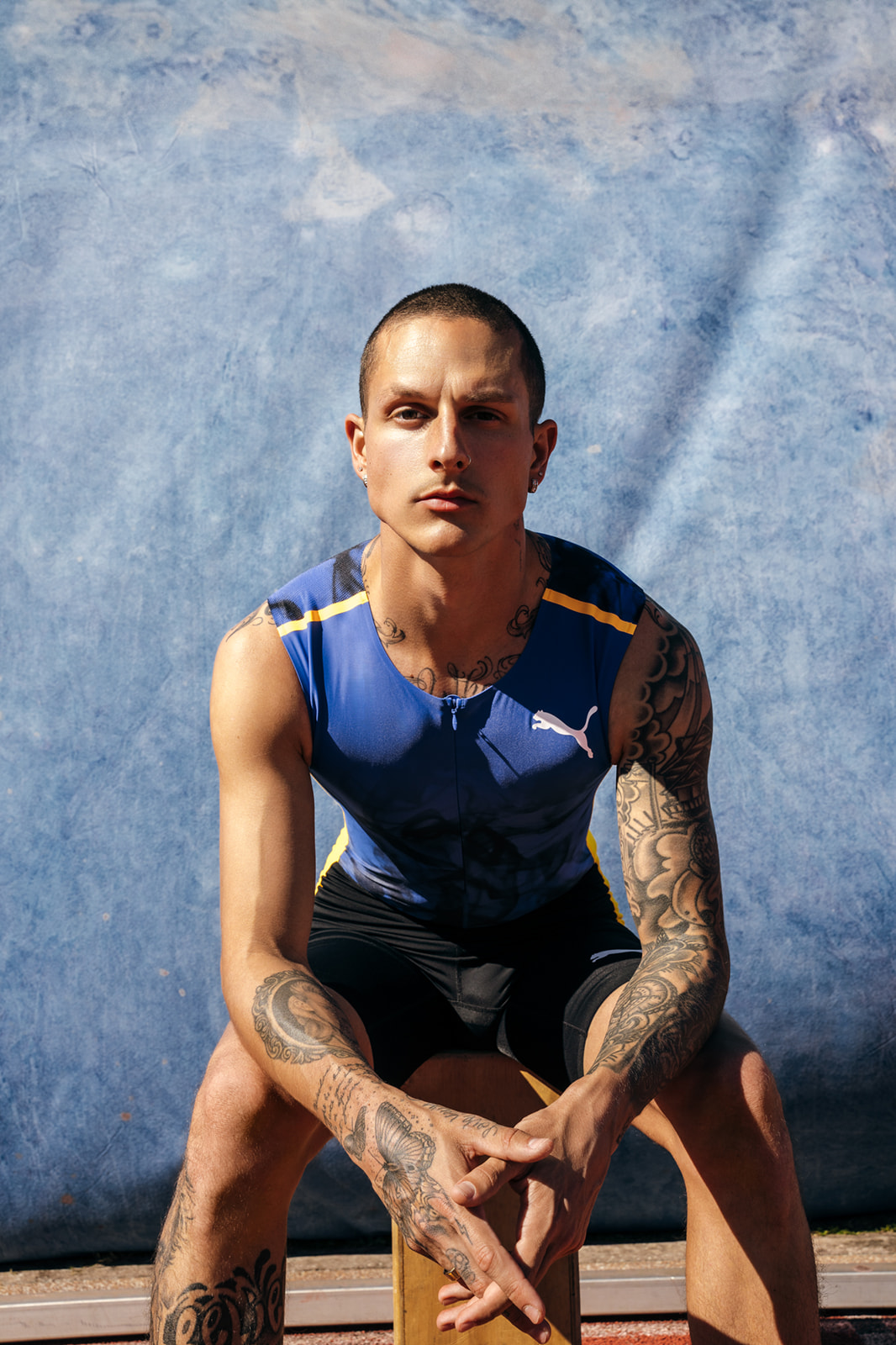Runner Nick Mayhugh sits in front of blue hand painted canvas by Ultraviolet Backdrops. Image by Benny Renee Studios 