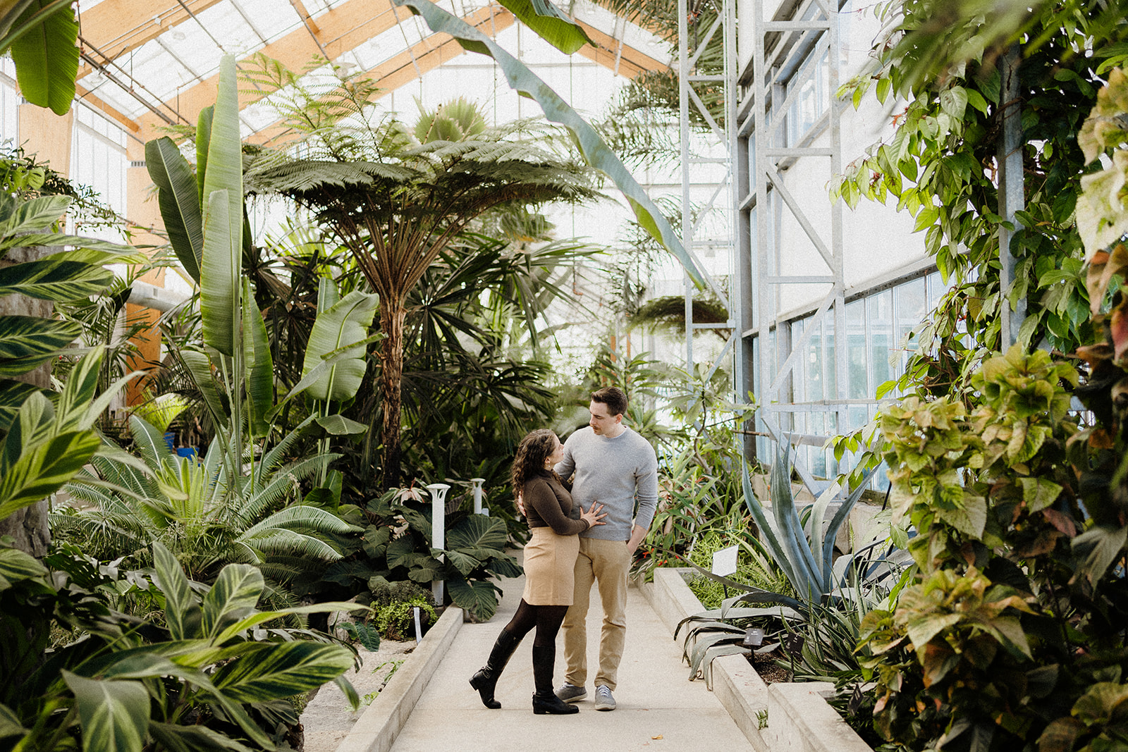 A man and woman standing beside each other in greenhouse.