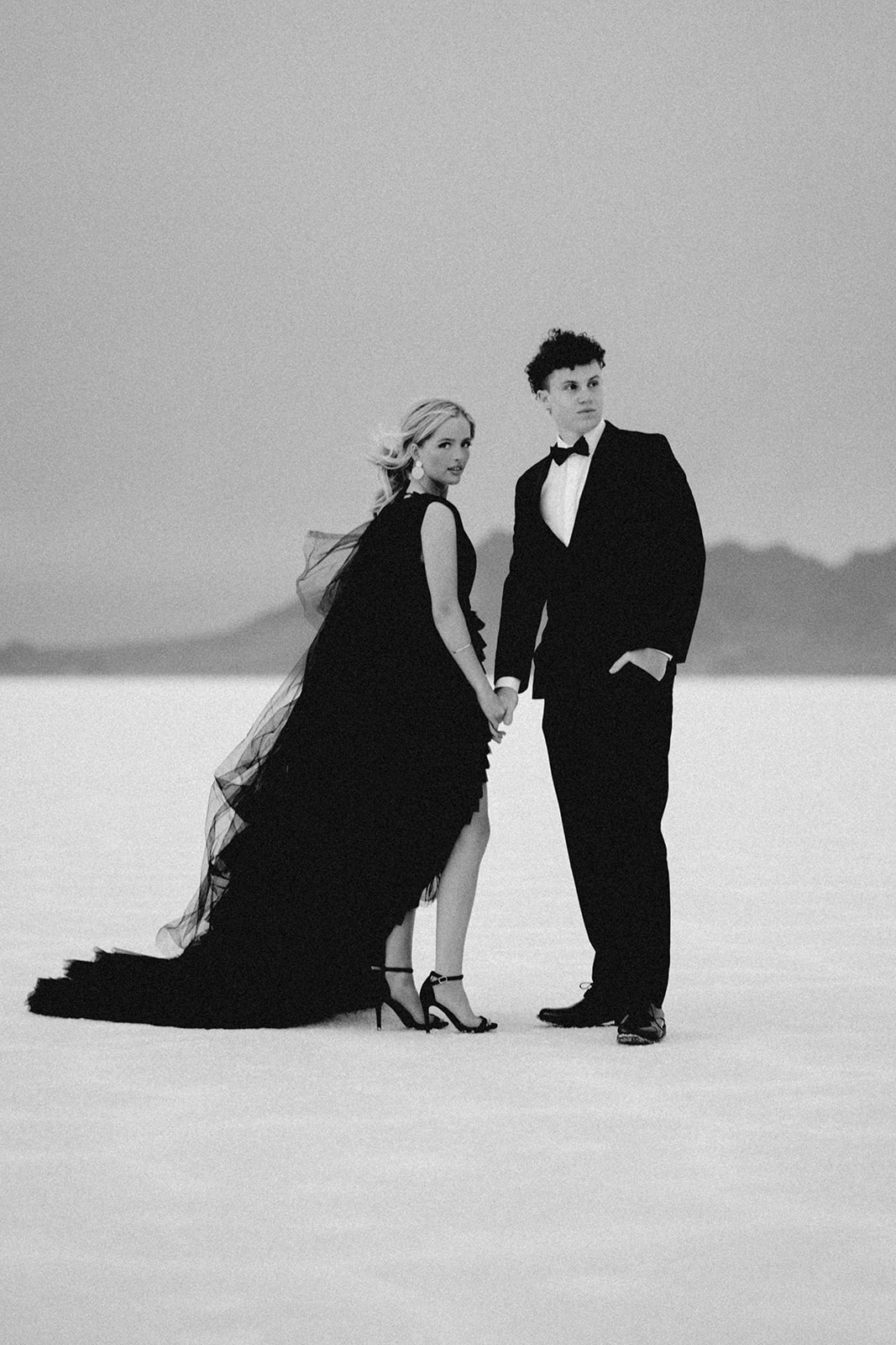 Classic black tuxedo in focus with woment black tulle dress at Utah photographer’s Salt Flats session.