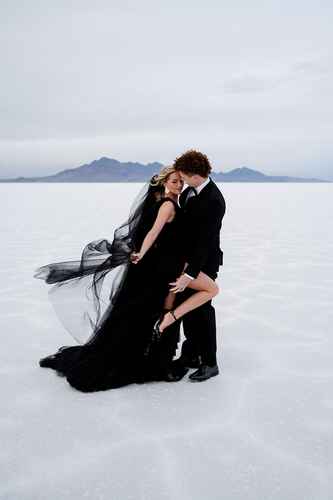 couple in formal attire kissing at the salt flats in utah