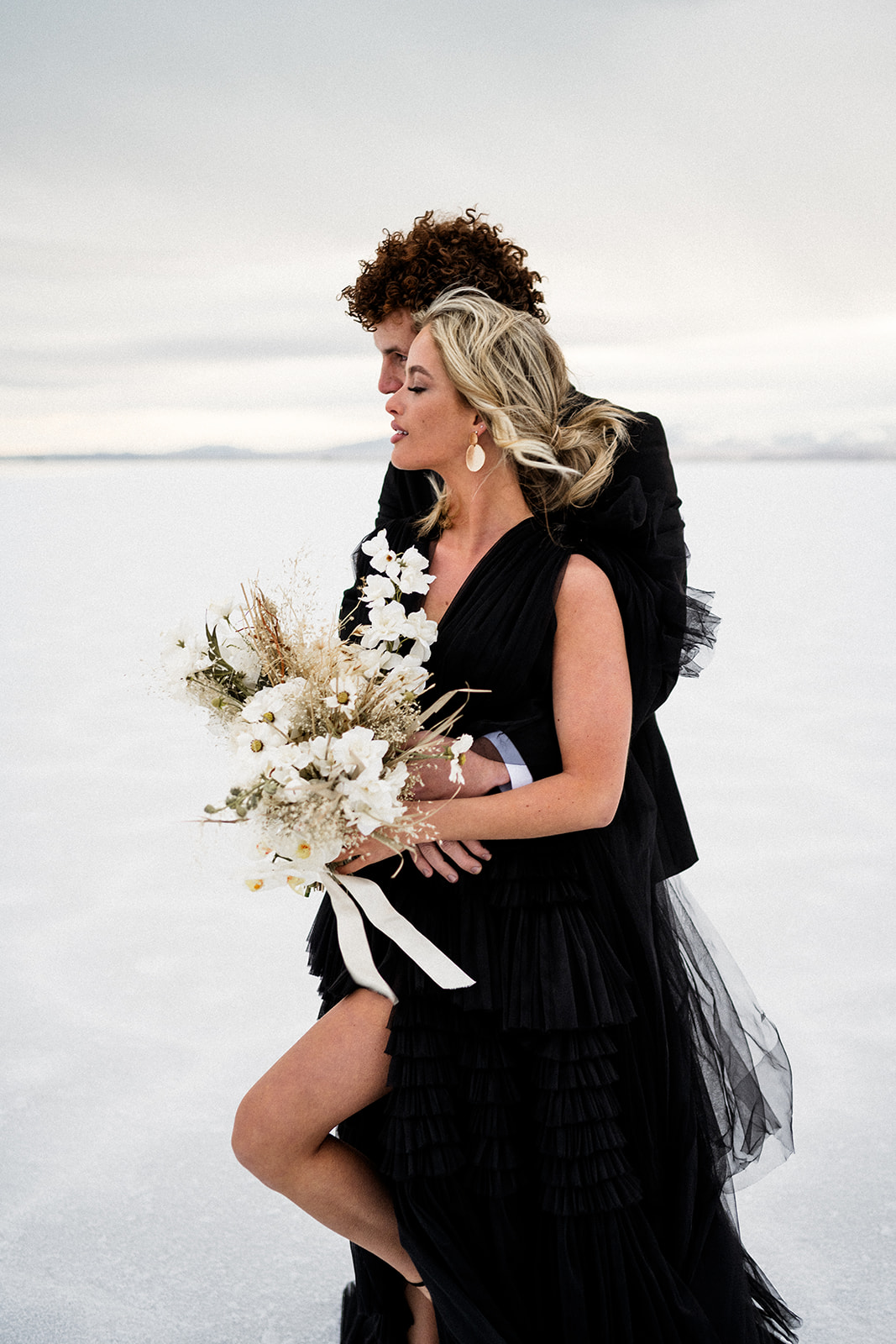 Couple holding a bouquet of flowers in formal attire at the Salt flats in utah