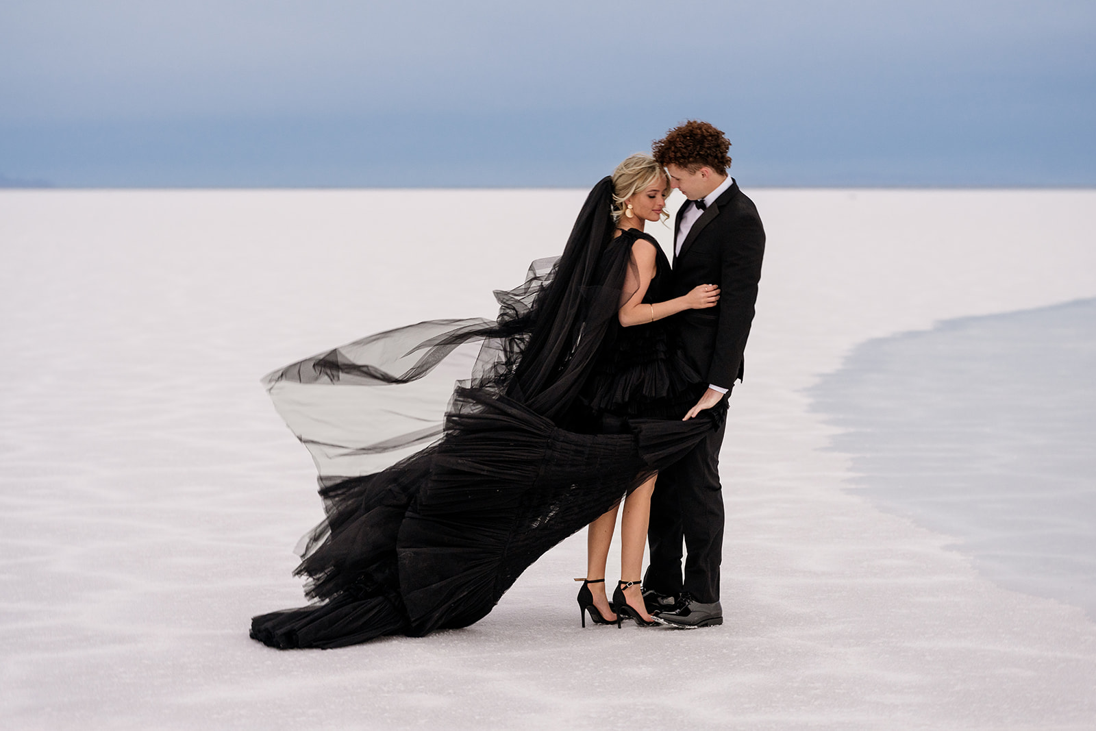 Couple hugging in the wind at the flooded utah salt flats