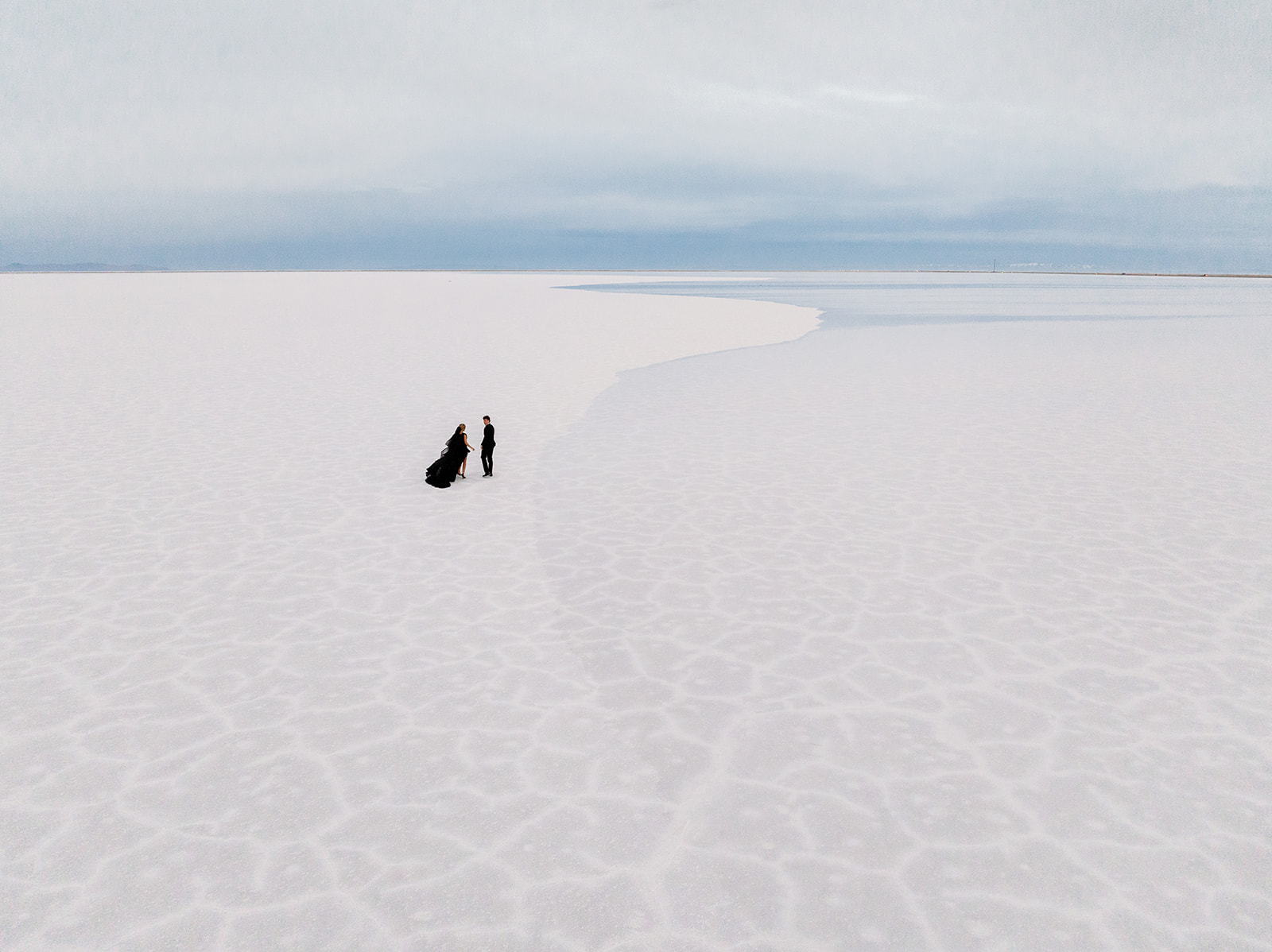 drone view photo of couple walking away on the textured salt flats