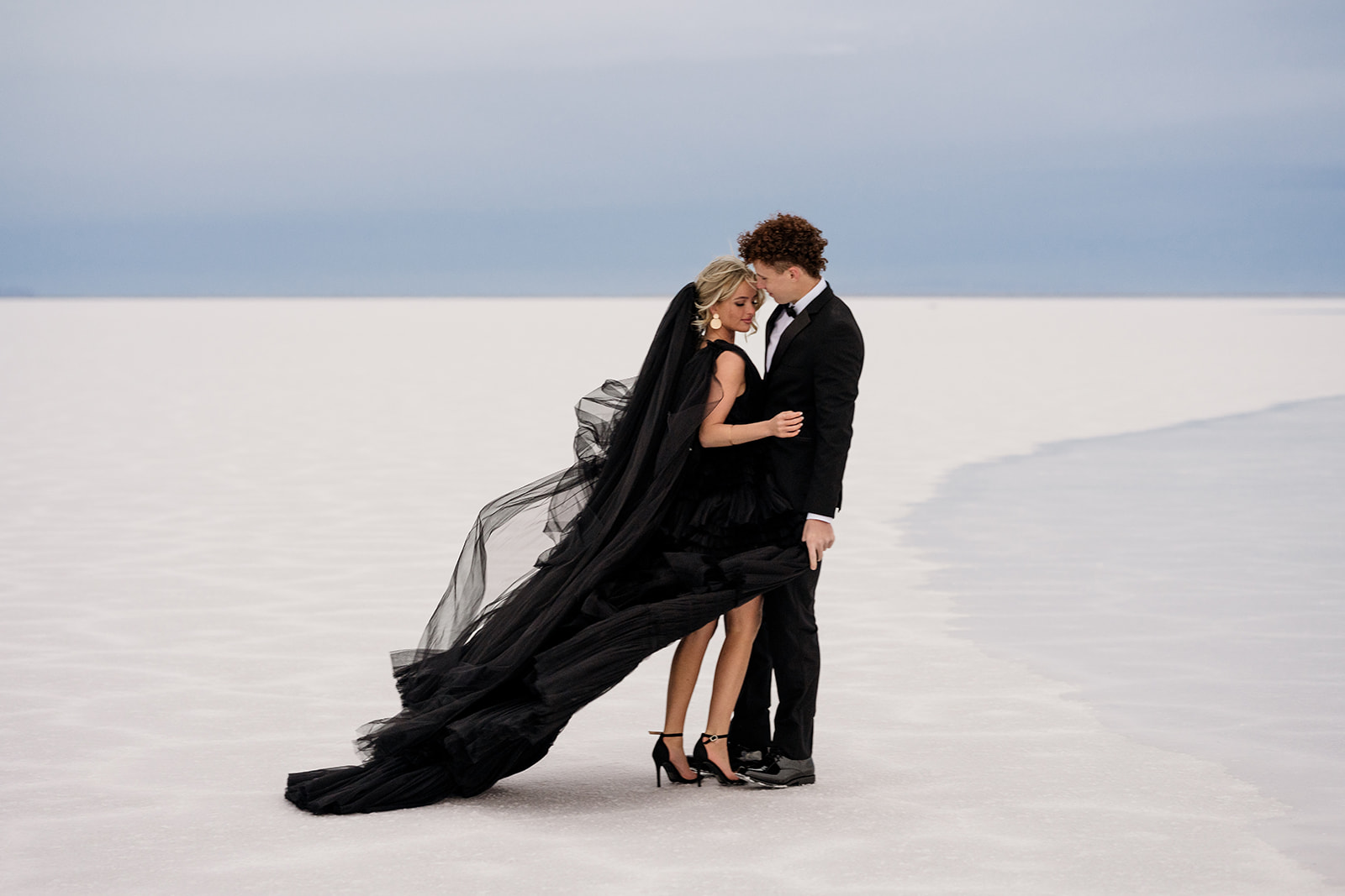 Engaged couple kiss framed by the vast beauty of Utah’s Salt Flats