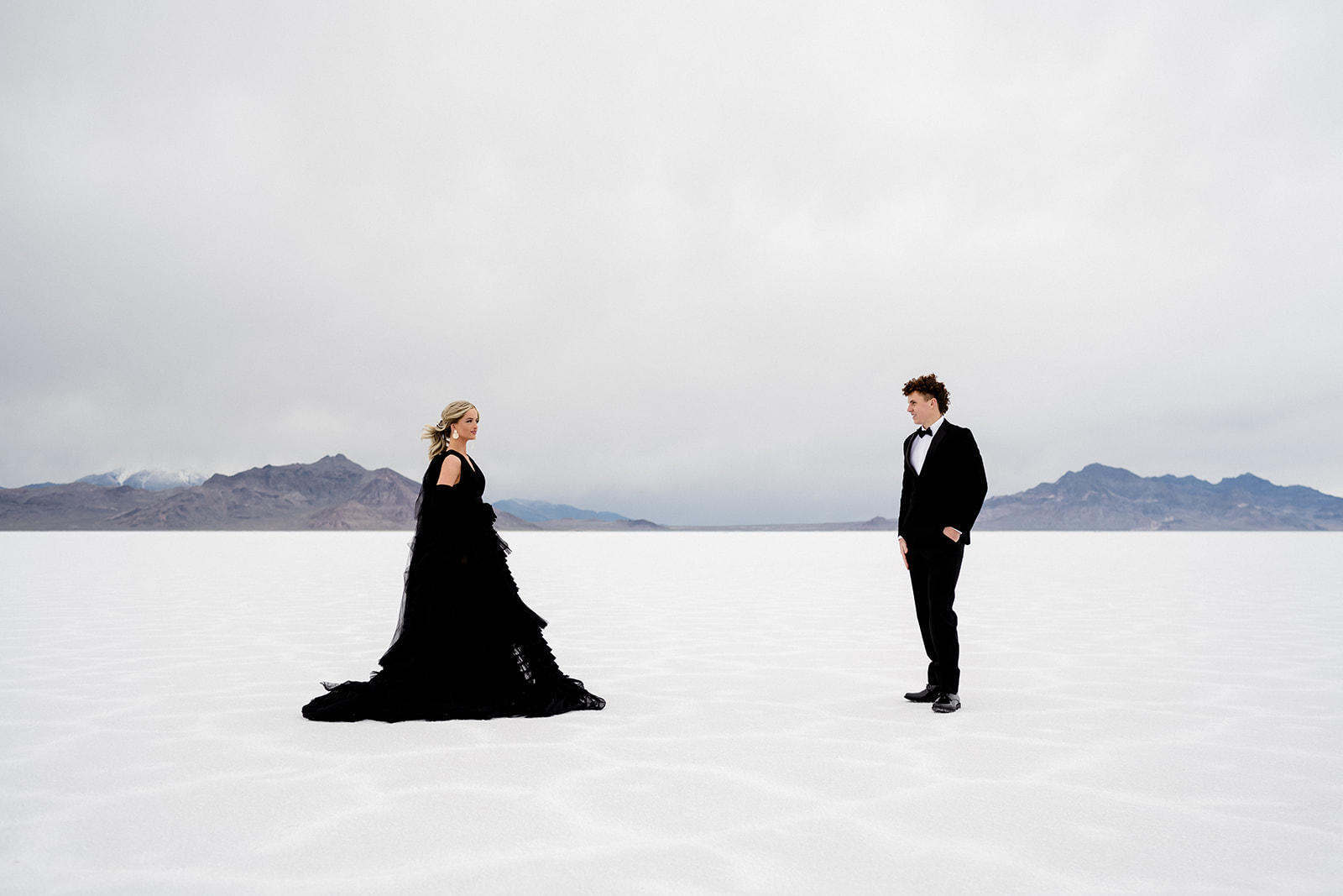 Engaged couple standing apart looking at each other adventurous spirit captured by Utah Salt Flats photographer