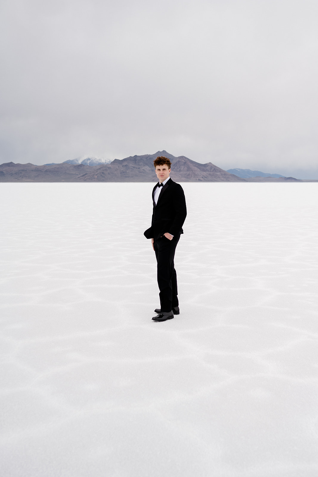 man in a tux standing on the salt flats at his couples photo shoot