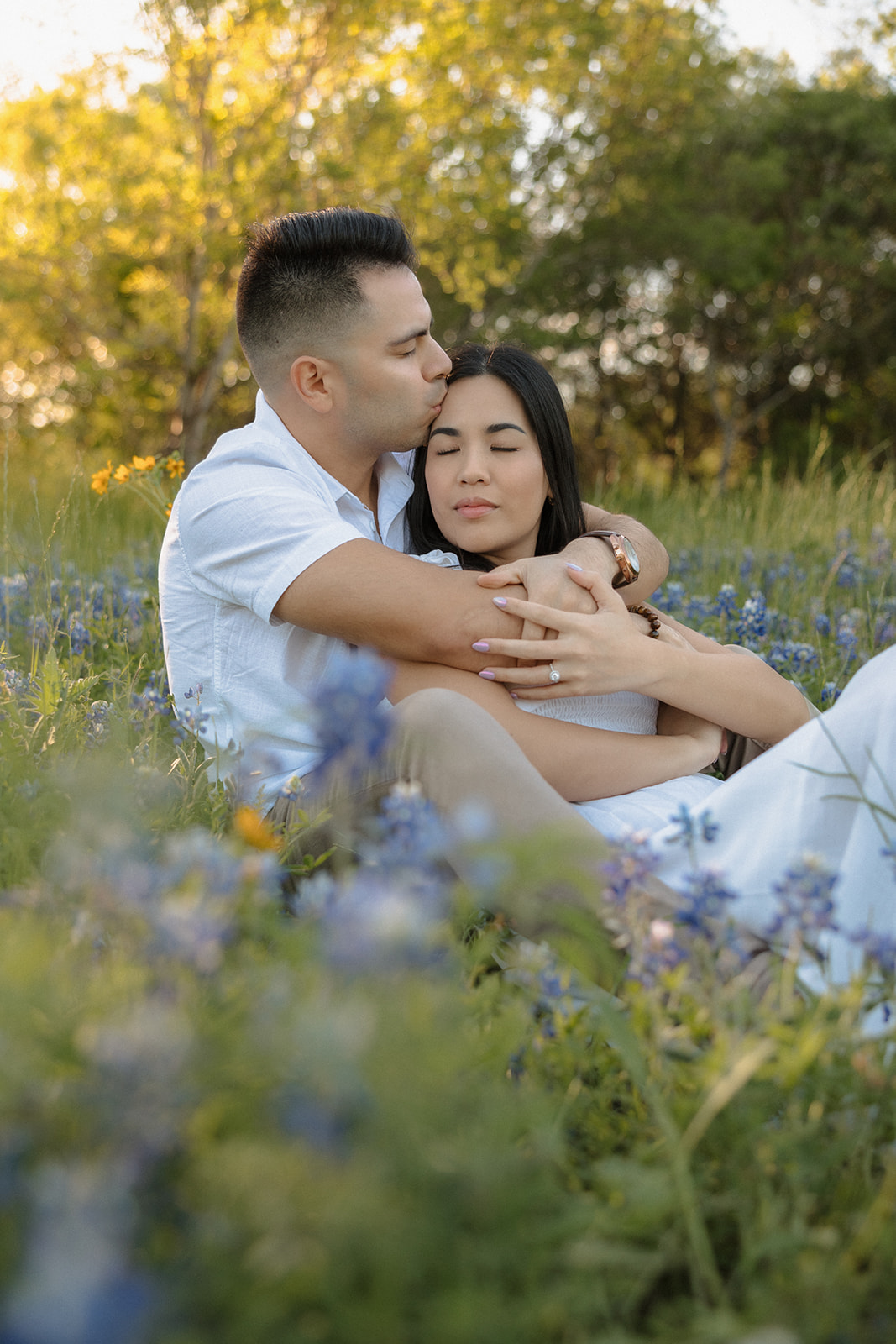Couple sitting in field of Bluebonnets kissing at McKinney Falls state park
