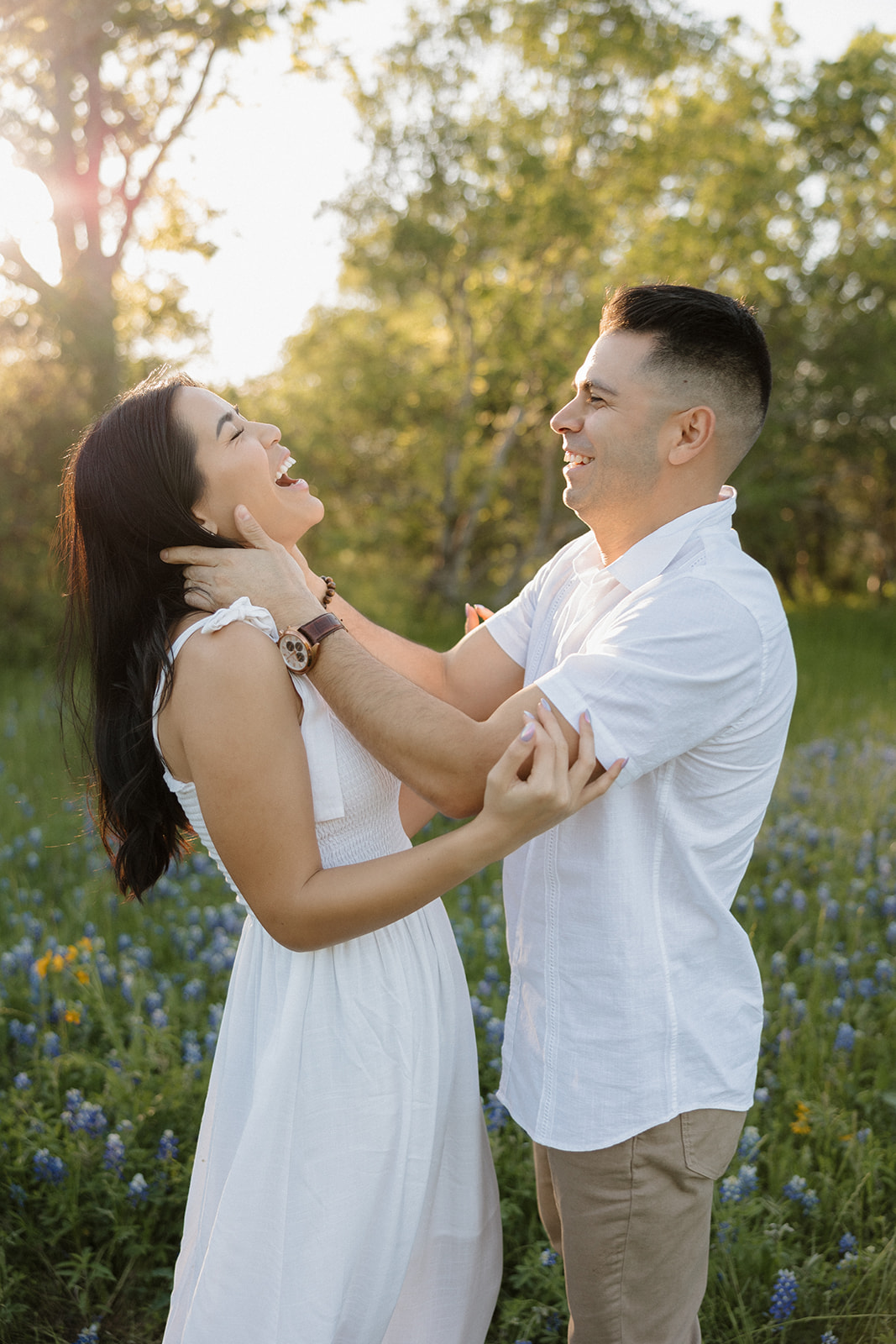 Couple wearing white laughing in a field of Bluebonnets at McKinney Falls state park