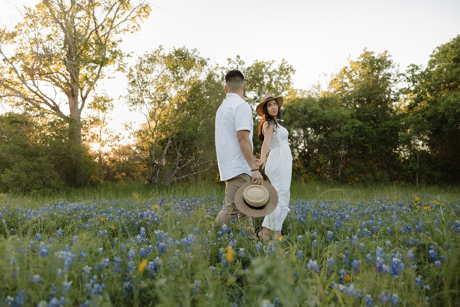 Couple wearing white hugging in a field of Bluebonnets at McKinney Falls state park