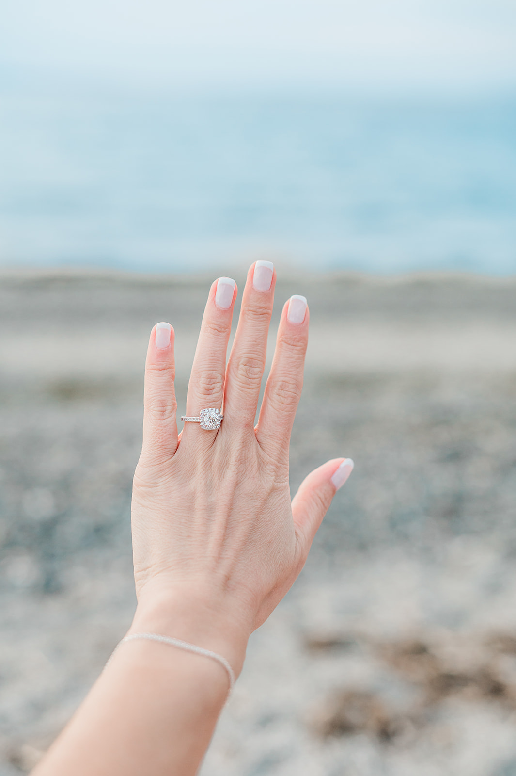 Halo engagement ring in front of coastline
