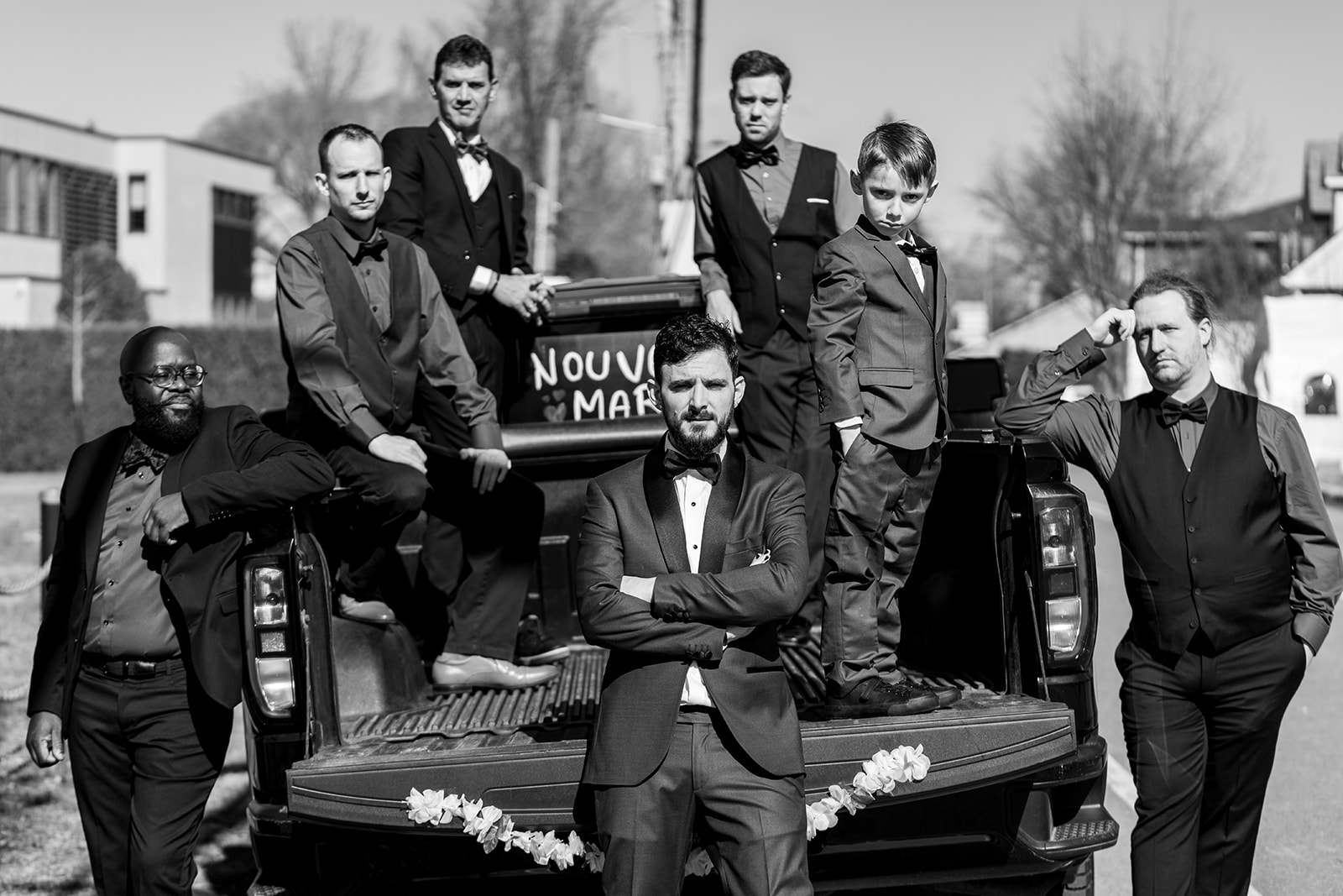 a black and white photograph of groomsmen with a pick up truck