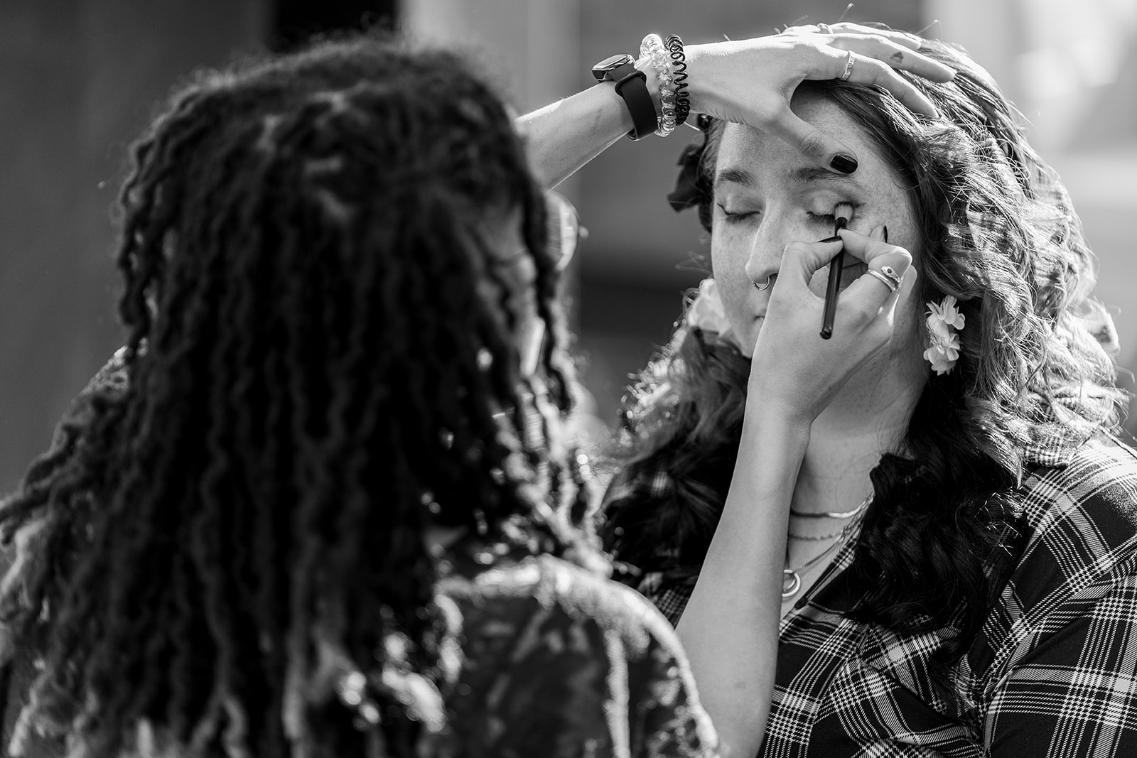 a black and white photography during bride prep where the bride is getting her make up done
