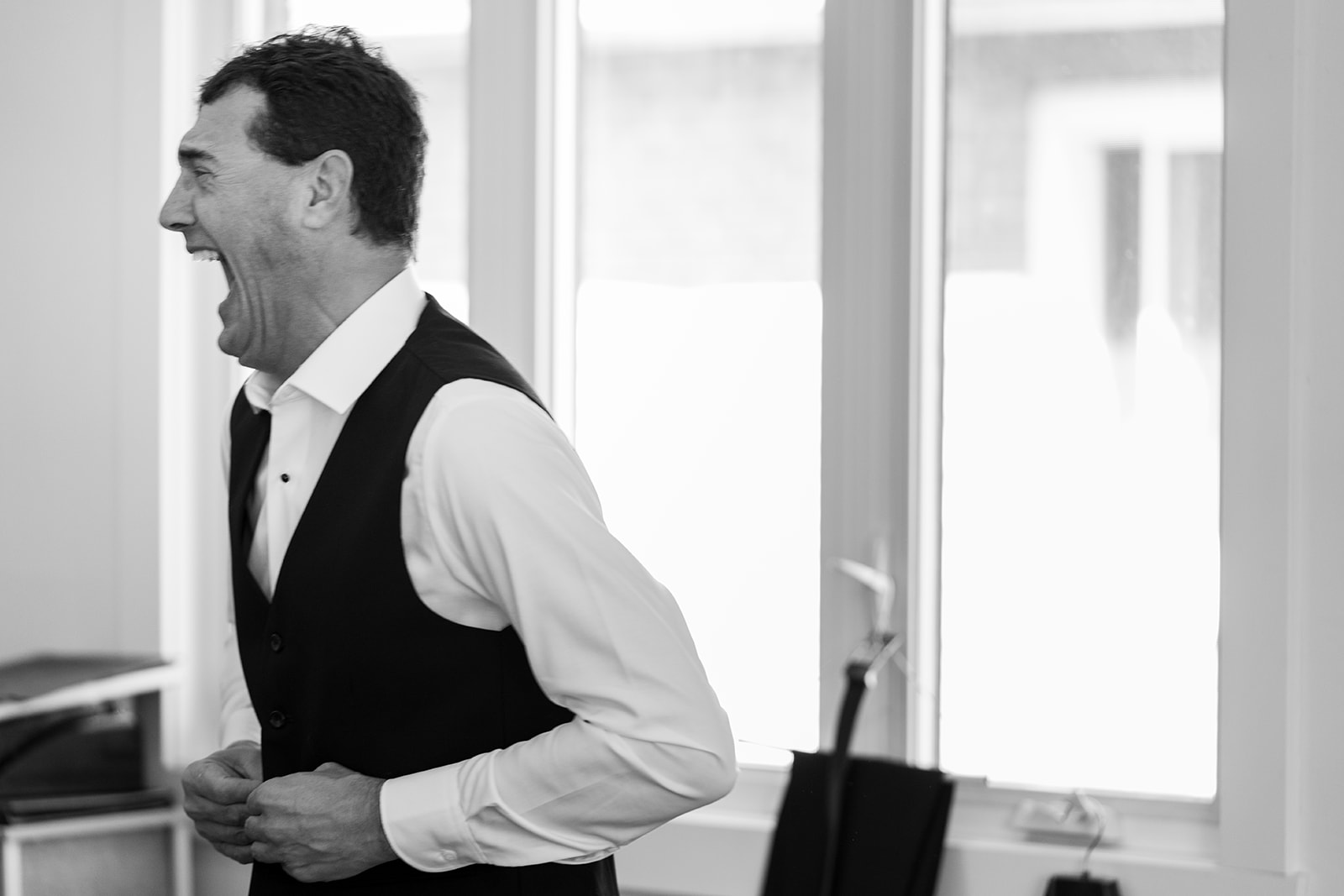 a black and white photography of the father of the groom getting dressed for his son's big day