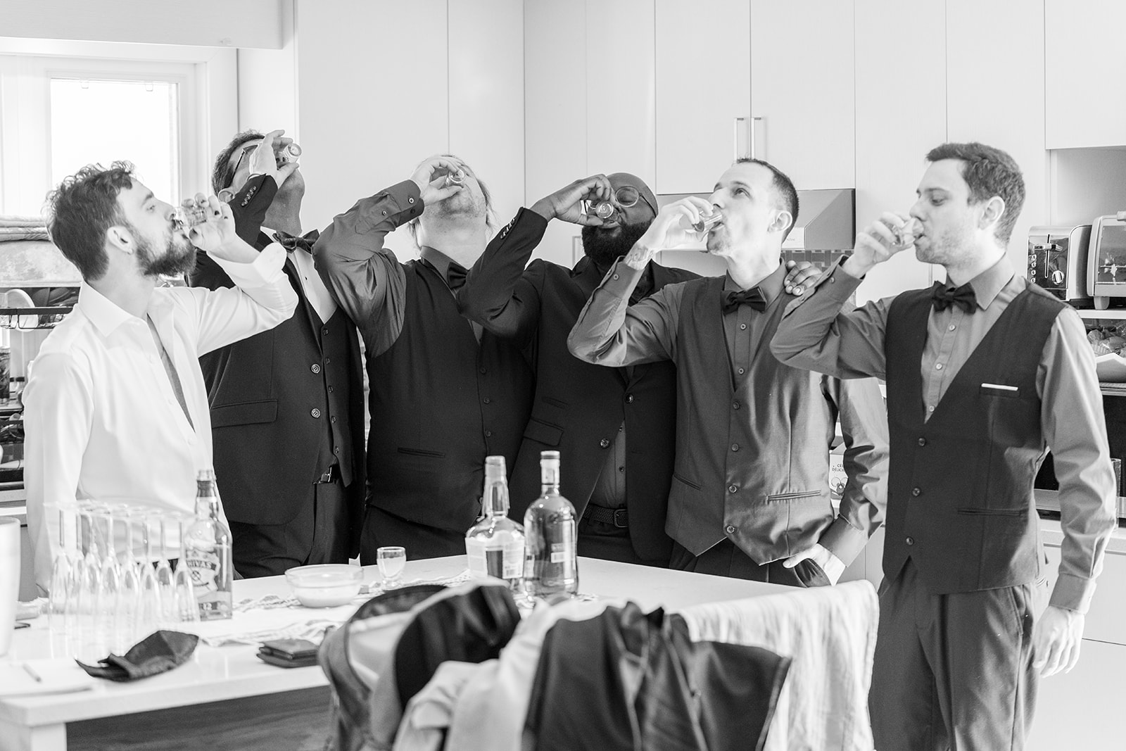 the groom and groomsmen taking a shot 