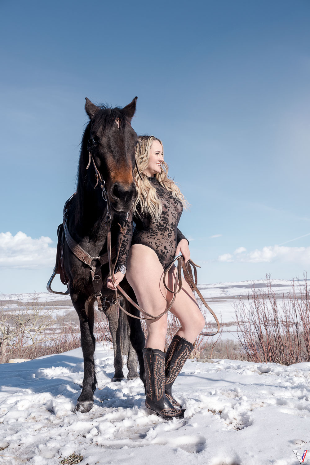 A lace bodysuit and cowboy boots are used to pose next to the horse. 