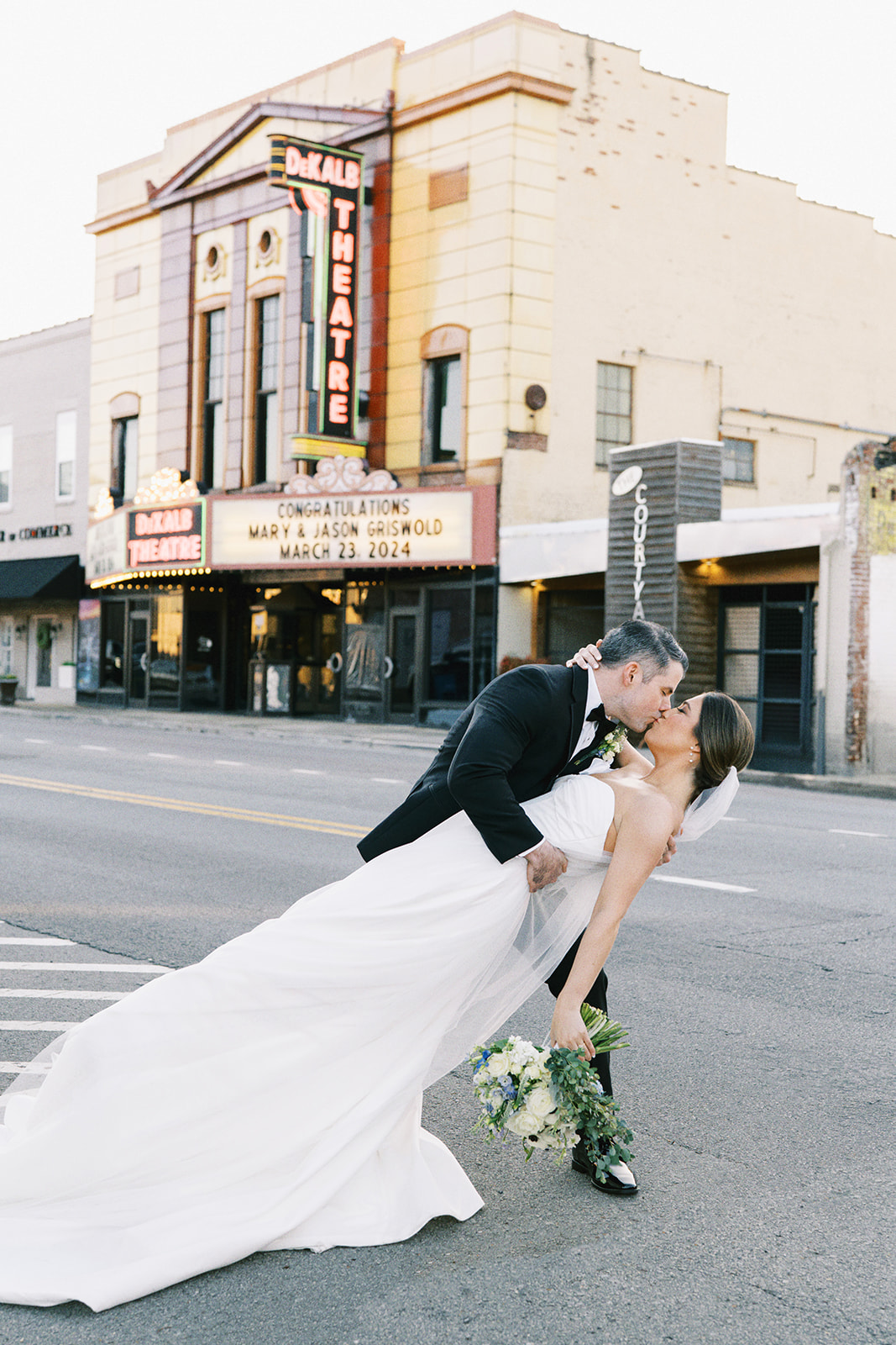 Bride and groom kiss in front of the marquee at DeKalb Theatre in Fort Payne, Alabama